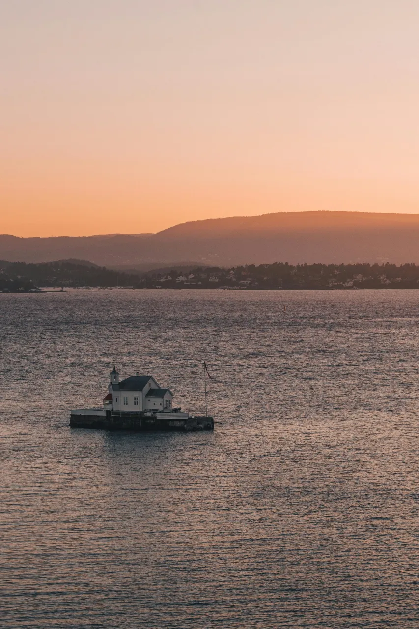 Oslofjord lighthouse at sunset with calm water and mountains