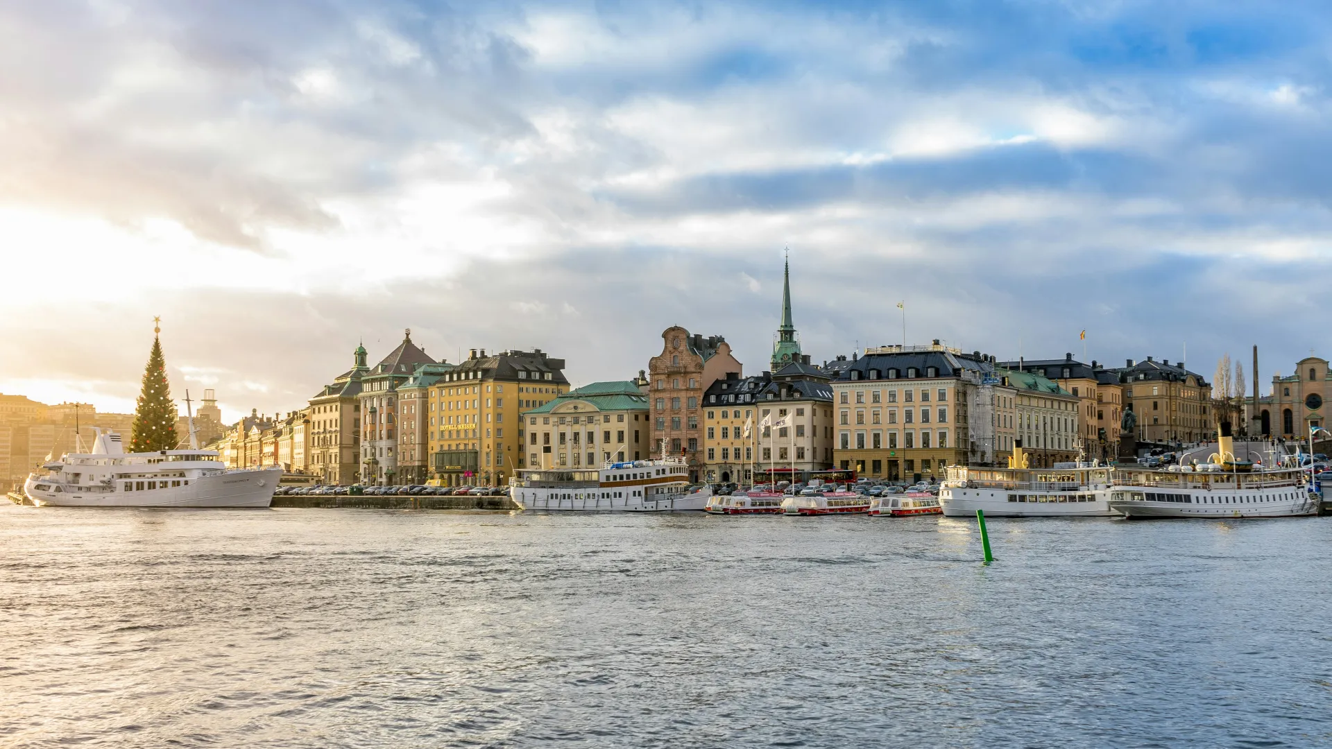 Waterfront view of Stockholm skyline with historic buildings, boats, and church spire