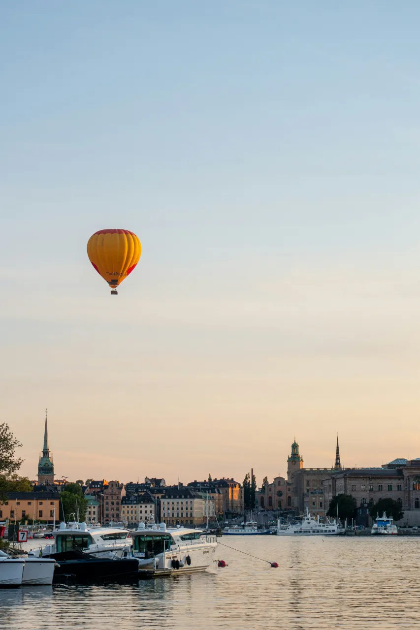Hot air balloon flying over Stockholm waterfront and historic skyline at golden hour