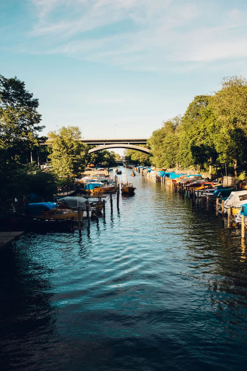 Stockholm canal view with boats, waterfront greenery and city bridge in summer